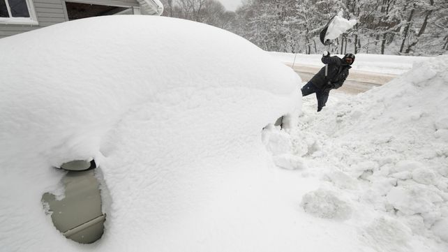 Un hombre intenta desenterrar su auto de la montaña de nieve en Erie