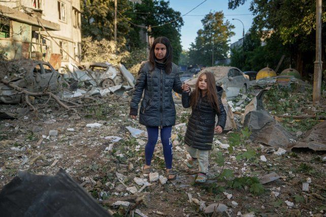 Una madre y su hija salen de su casa en Kiev después de un ataque ruso.