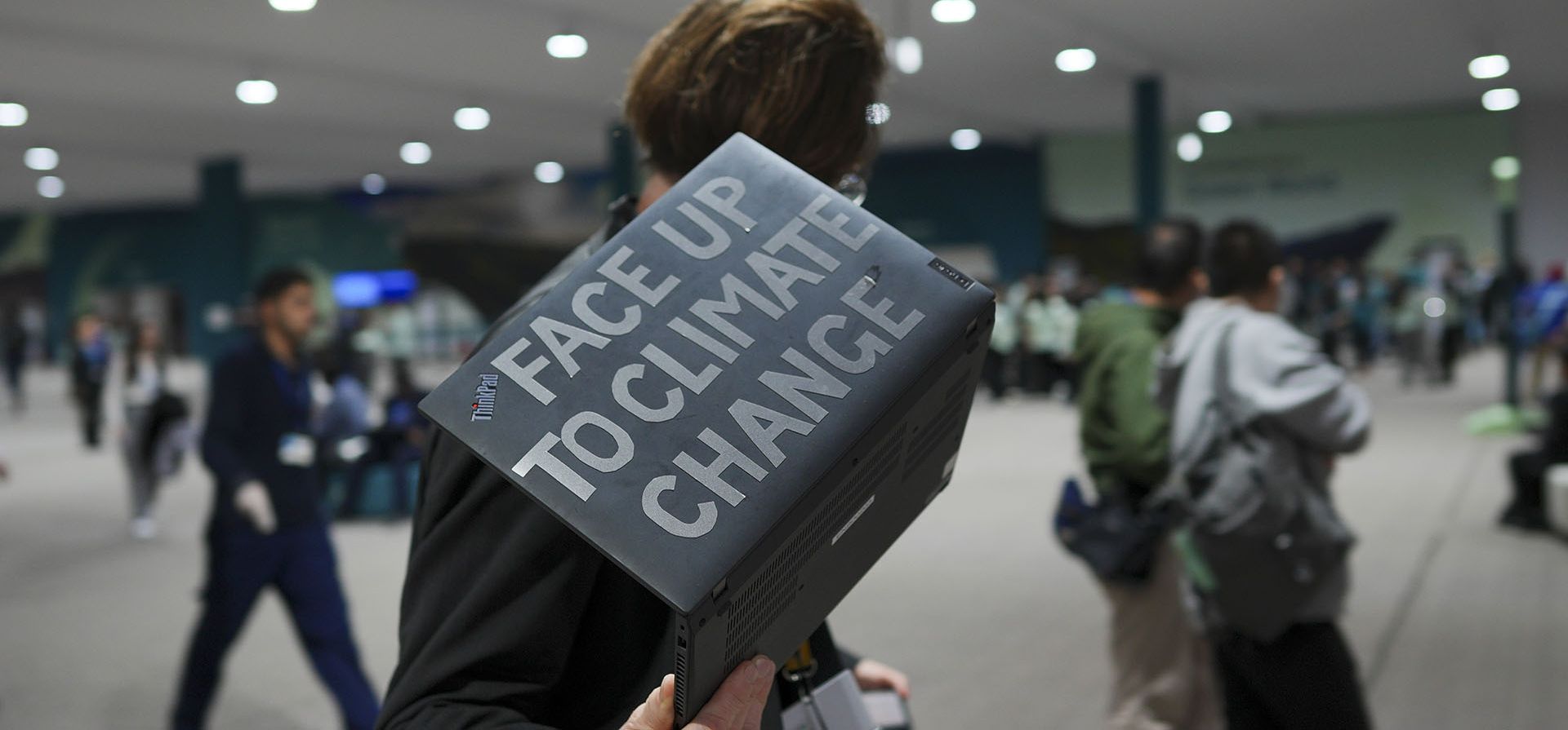 Un asistente camina por la Cumbre del Clima de la ONU COP29 con una computadora portátil que lee Un asistente camina por la Cumbre del Clima de la ONU COP29 con una computadora portátil que lee