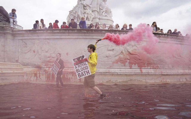 Manifestantes del grupo activista climática Extinction Rebellion embadurnan de pintura roja el Monumento a la Reina Victoria fuera de las puertas del Palacio de Buckingham en protesta contra la caza de animales, en Londres.