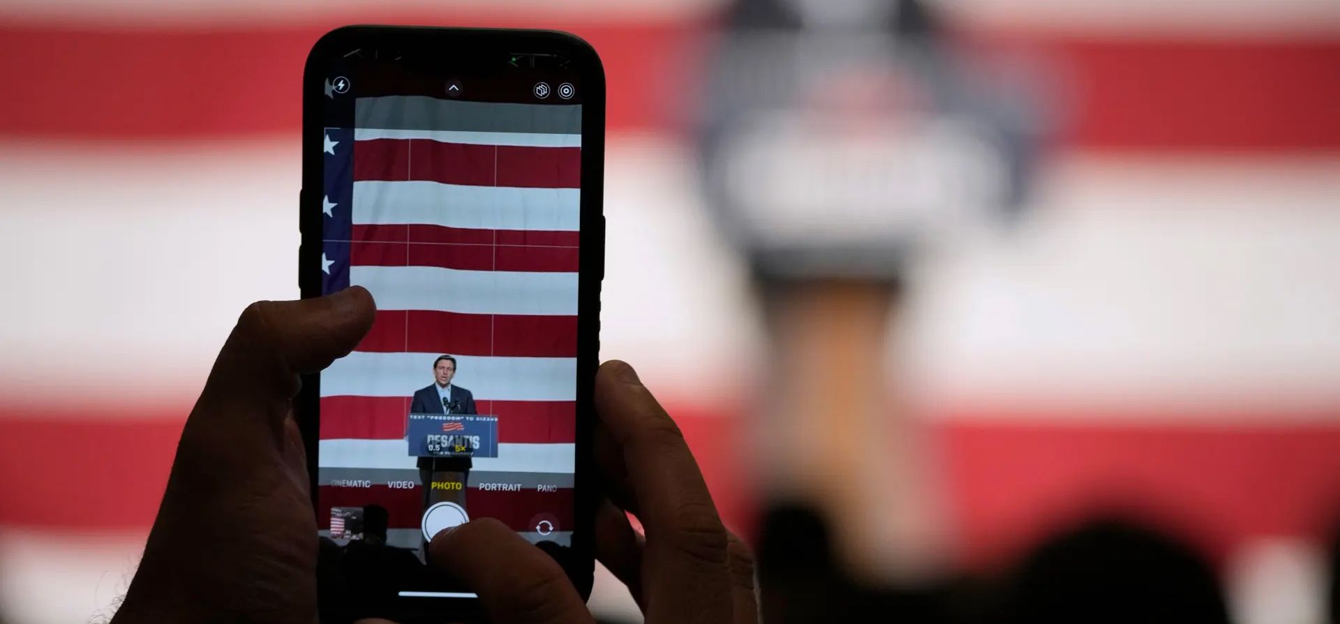 Iowa, Estados Unidos. Un miembro de la audiencia toma una foto mientras el candidato presidencial republicano Ron DeSantis habla durante un evento de campaña. Fotografía: Charlie Neibergall/AP Iowa, Estados Unidos. Un miembro de la audiencia toma una foto mientras el candidato presidencial republicano Ron DeSantis habla durante un evento de campaña. Fotografía: Charlie Neibergall/AP