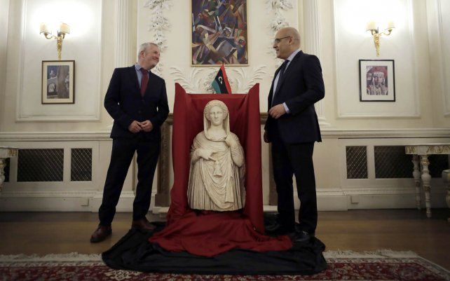 Mohamed Elkoni, encargado de Negocios de la embajada de Libia, y Peter John Higgs del Museo Británico posan junto a una estatua funeraria del siglo II a.C. de la antigua ciudad griega de Cirene, que se cree que representa a la diosa Deméter o más probablemente a su hija.