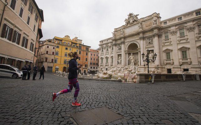 Una mujer corre por la histórica Fontana di Trevi de Roma. La mitad de las regiones de Italia entraron el lunes en la forma más estricta de bloqueo en un intento por frenar el último aumento en las infecciones por coronavirus.