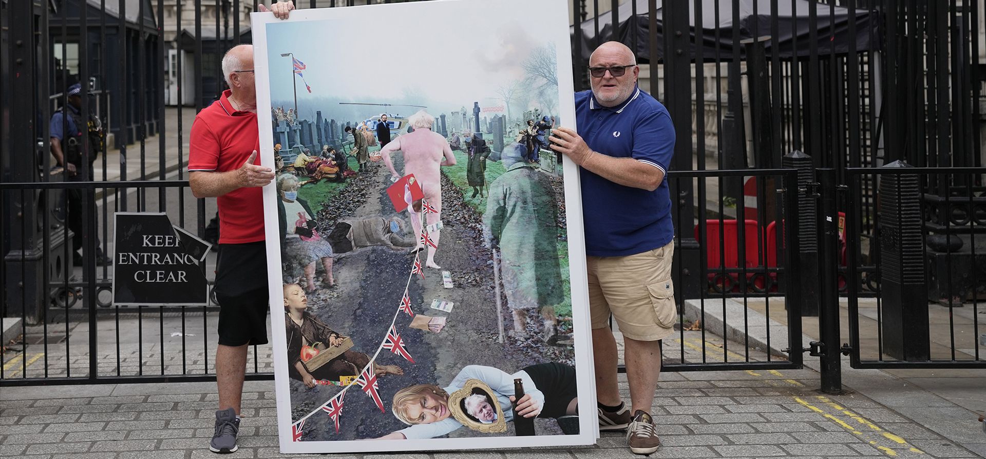 Dos miembros del grupo de campaña por la democracia Gran Bretaña Abierta sostienen una tarjeta de despedida gigante que representa al primer ministro británico Boris Johnson, frente a las puertas de Downing Street en Londres, el viernes 2 de septiembre de 2022. 