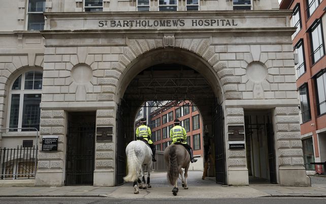 Policías a caballo transitan a través de un arco de entrada al Hospital de San Bartolomé en Londres