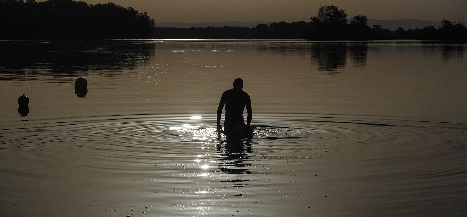 Un hombre camina en el agua mientras el sol sale sobre el lago Miribel, en las afueras de Lyon, en el centro de Francia. Una capa de aire caliente que se extiende desde el Mediterráneo hasta el Mar del Norte está dando a gran parte de Europa occidental una ola de calor, con temperaturas pronosticadas que superen los 30 grados centígrados desde Málaga a Londres este viernes.