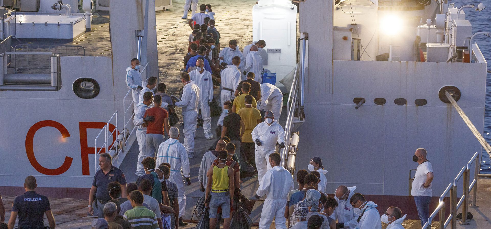 Migrantes esperan para abordar un barco de la Guardia Costera italiana en la isla siciliana de Lampedusa, Italia, el miércoles 3 de agosto de 2022. El ex ministro del Interior de Italia, Matteo Salvini, está haciendo campaña para recuperar su antiguo trabajo. Salvini hará una parada el jueves en la isla más meridional de Italia, Lampedusa, la puerta de entrada a decenas de miles de inmigrantes que llegan a Italia cada año a través del peligroso mar Mediterráneo central.