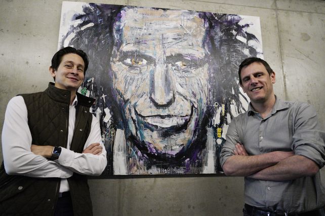 Matías y Marcelo posando con una pintura original del músico Keith Richards, que decora las oficinas de 3dF.