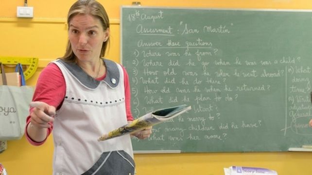 teacher. Una profesora al frente de una clase. El sistema educativo presenta fallas y carencias en cuanto a metas y evaluaciones.