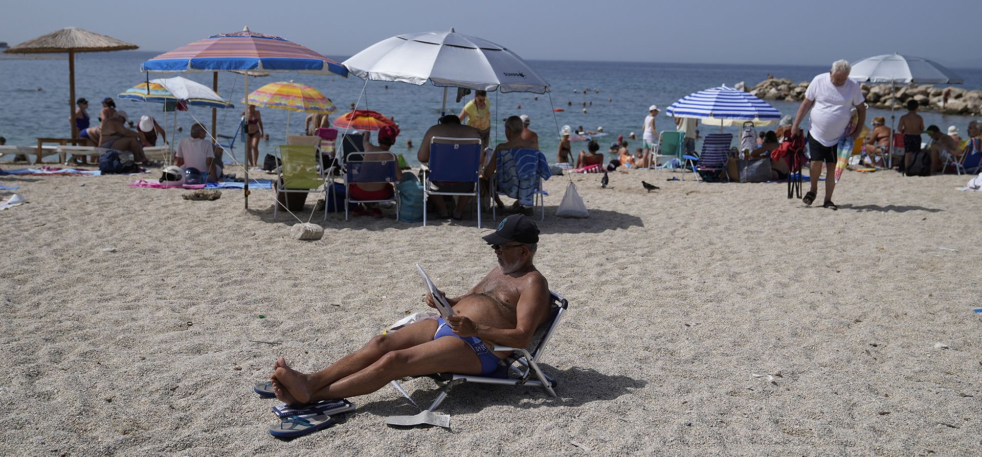 Un hombre lee un periódico en la playa pública de Alimos, en el sur de Atenas, Grecia, el jueves 23 de junio de 2022. Las temperaturas alcanzaron los 40 °C en partes del sur de Grecia el viernes cuando una ola de calor de junio azotó áreas en Europa Central.
