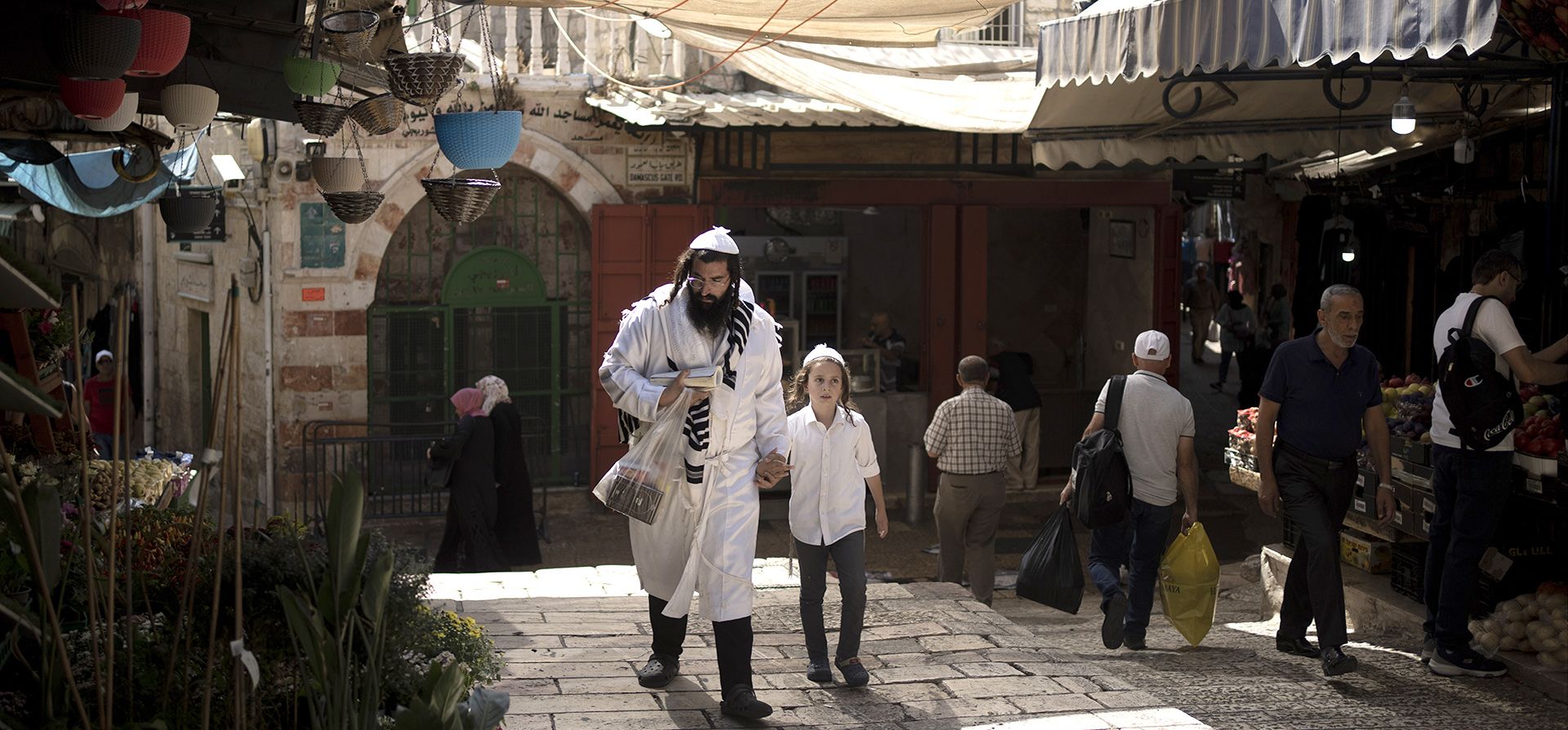 Un padre y un hijo judíos ultraortodoxos caminan por un área de mercado cerca de la Puerta de Damasco en la Ciudad Vieja de Jerusalén en Yom Kippur, el Día de la Expiación judío, el miércoles 5 de octubre de 2022.