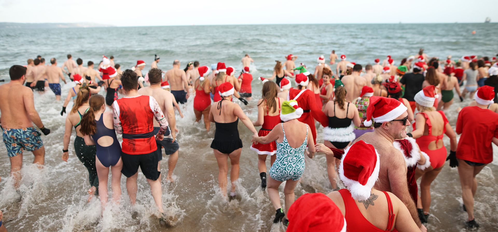 La gente se lanza al mar en la Bahía de Helen, Irlanda del Norte, para el baño anual de Nochebuena en las frías aguas del lago Belfast Lough con el fin de recaudar fondos para Dementia NI y Air Ambulance NI, el miércoles 24 de diciembre de 2025. (Foto AP/Peter Morrison)