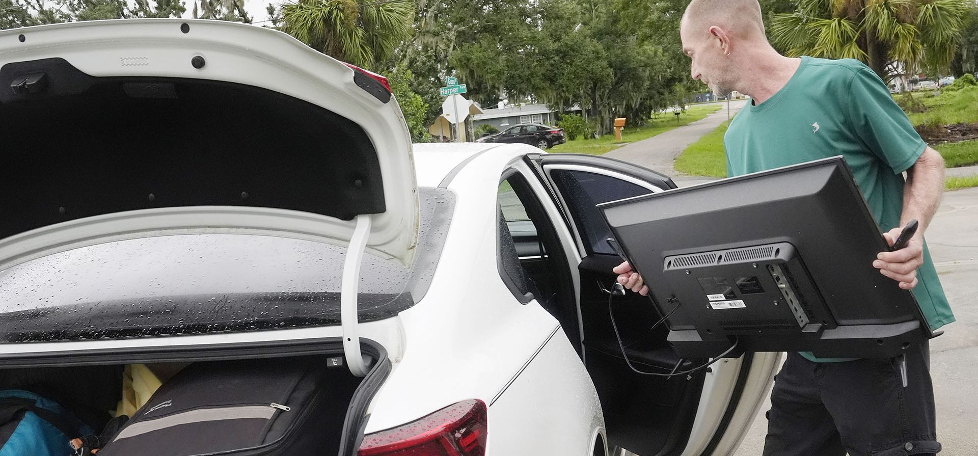 Josh Parks carga su televisor en su auto mientras se prepara para evacuar a la casa de su hija antes del huracán Milton, el miércoles 9 de octubre de 2024, en Port Charlotte, Florida. (Foto AP/Marta Lavandier)