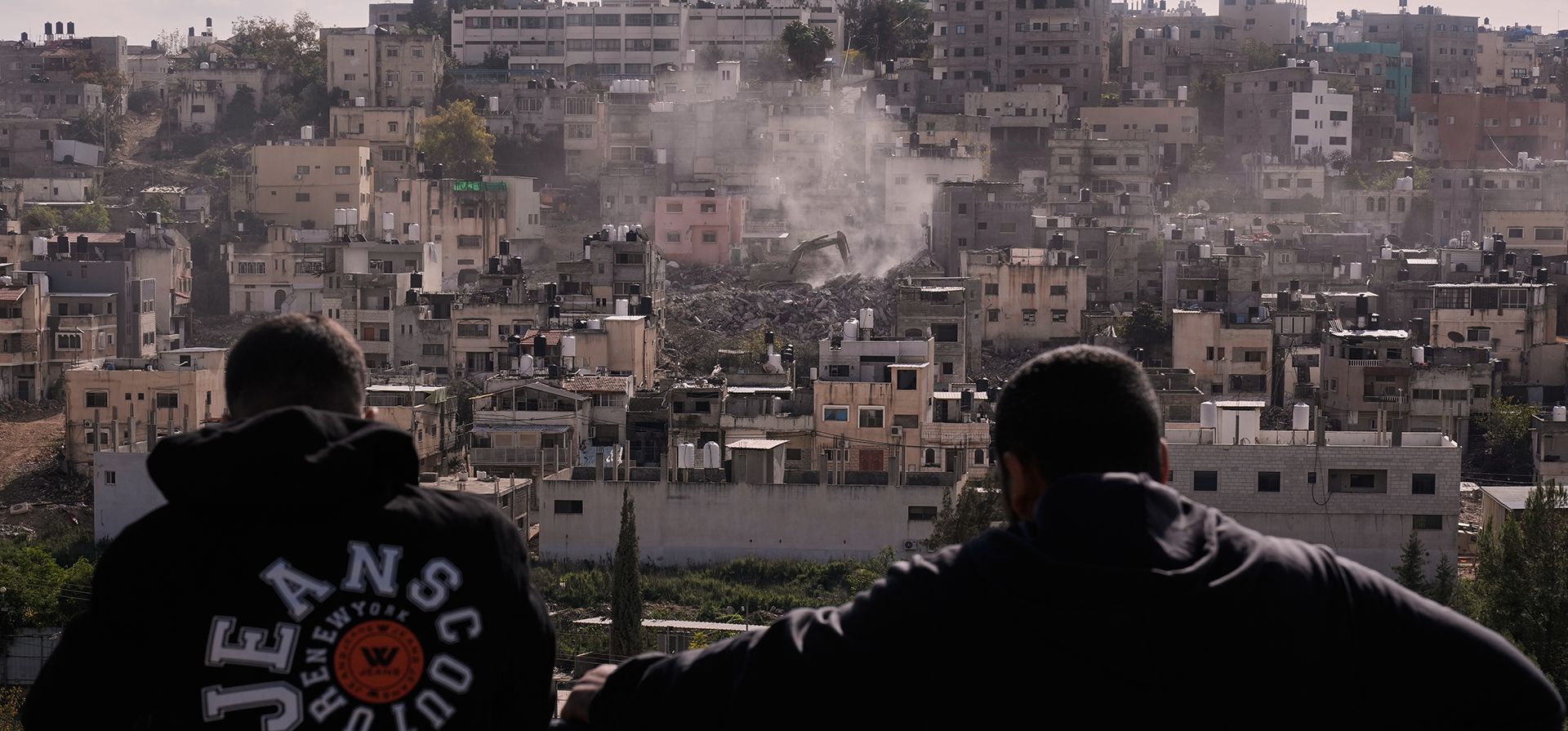 Personas observan cómo una excavadora del ejército israelí demuele viviendas en el campo de refugiados urbanos palestinos de Nur Shams, cerca de la ciudad cisjordana de Tulkarem, el miércoles 31 de diciembre de 2025. (Foto AP/Majdi Mohammed) Personas observan cómo una excavadora del ejército israelí demuele viviendas en el campo de refugiados urbanos palestinos de Nur Shams, cerca de la ciudad cisjordana de Tulkarem, el miércoles 31 de diciembre de 2025. (Foto AP/Majdi Mohammed)