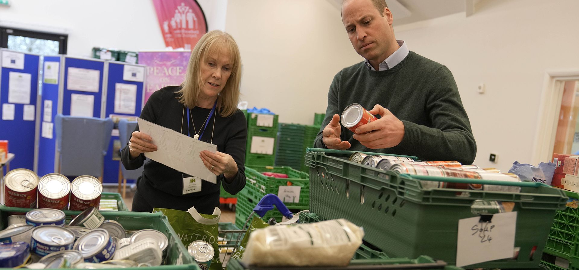 El Príncipe William revisa la etiqueta de una lata durante una visita a Windsor Foodshare en Windsor, el jueves 26 de enero de 2023. El Príncipe y la Princesa de Gales aprendieron más sobre el apoyo que la organización brinda a las personas y familias que viven en el área local, antes de ayudar a los voluntarios a clasificar las donaciones de alimentos y preparar paquetes para los clientes de la organización benéfica. (AP Photo/Alastair Grant, Pool)
