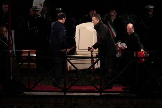 Funcionarios del Vaticano quitan el sillón que iba a ocupar el Papa Francisco durante la ceremonia.