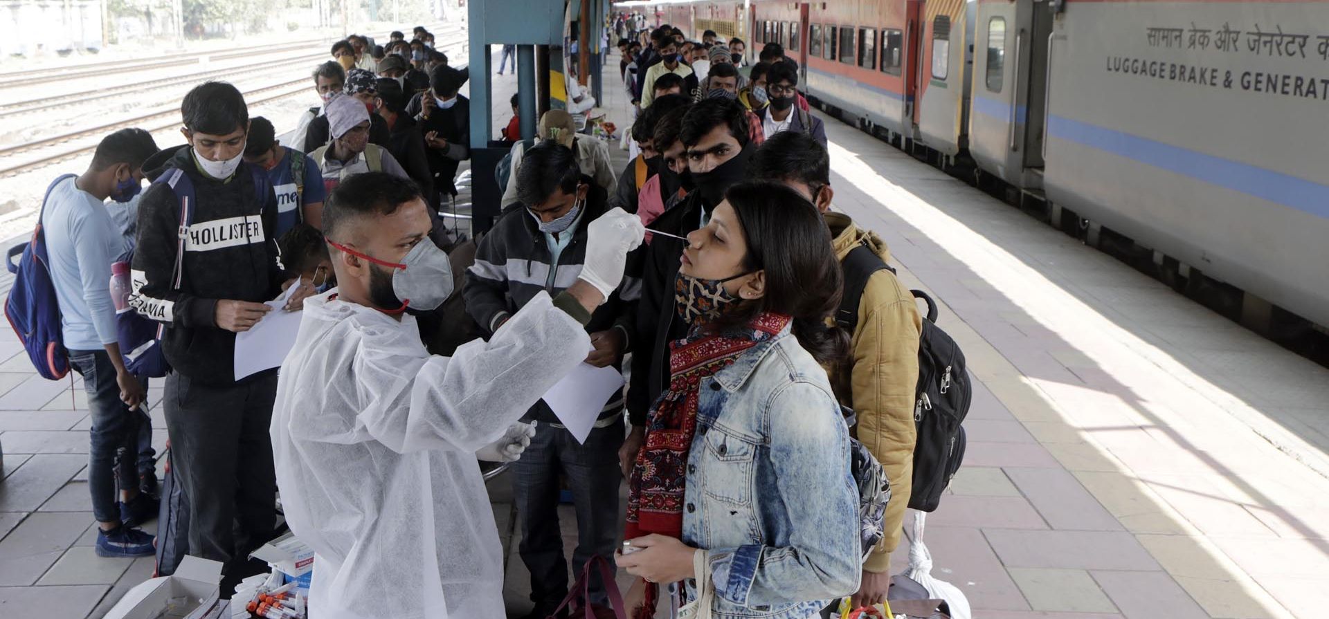 Un trabajador de la salud toma una muestra de hisopo de un viajero en una estación de tren para realizar una prueba de COVID-19 antes de permitirle ingresar a la ciudad, en Mumbai, India, el miércoles 12 de enero de 2022.