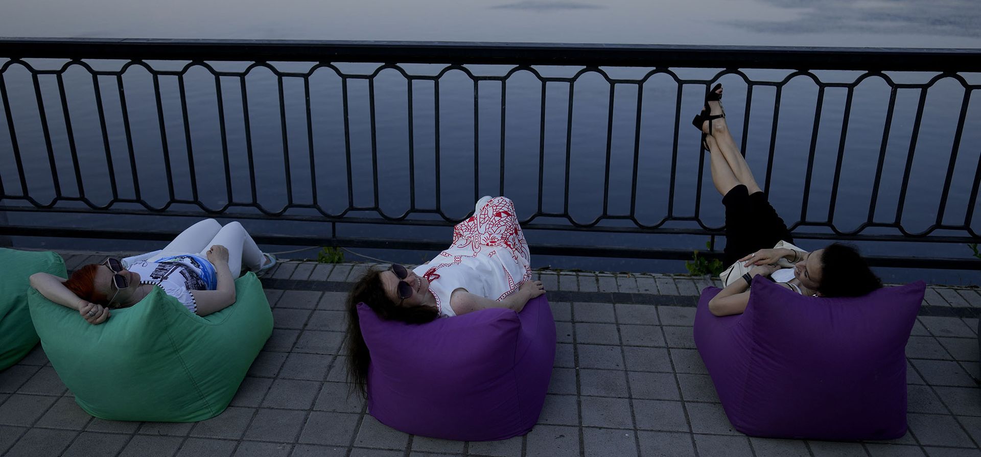 Las mujeres descansan frente al río Dniéper en Kyiv, Ucrania. El sol brilla pero reina la tristeza y la sombría determinación.