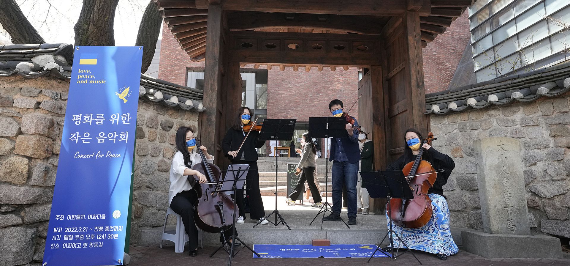 Profesores y estudiantes de la Universidad de Mujeres Ewha con máscaras con los colores de la bandera de Ucrania realizan un mini concierto al aire libre por la paz ,en Seúl, Corea del Sur, el miércoles 6 de abril de 2022.