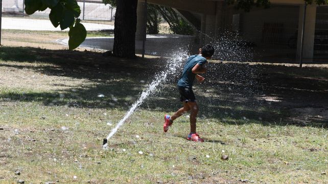 Un chico en Mendoza aprovecha el chorro de agua para refrescarse en un parque de la capital.&nbsp;