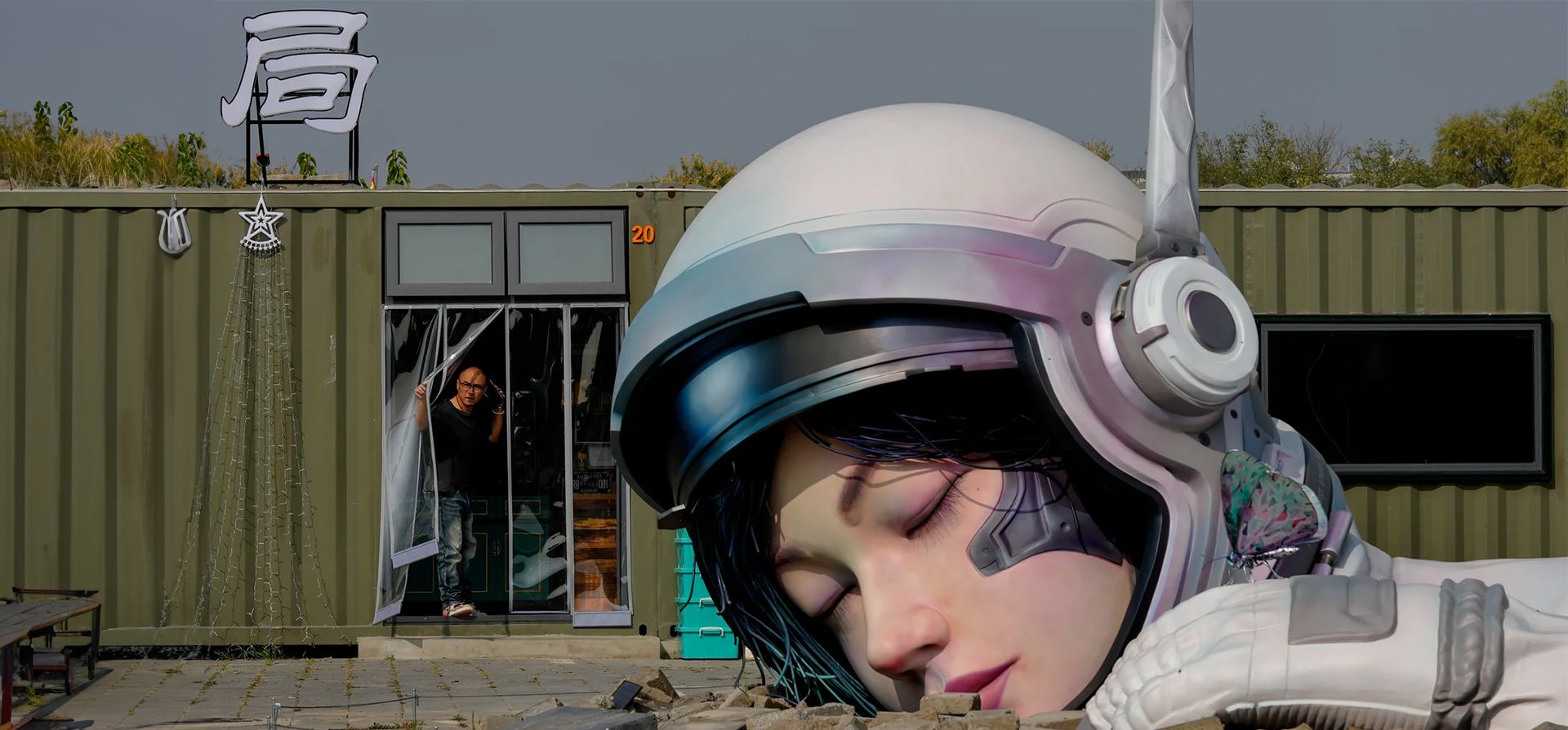 Un hombre mira desde un restaurante cerca de una escultura que representa a un astronauta chino dormido en el distrito artístico de Songzhuang, Pekín, China. Fotografía: Andy Wong/AP Un hombre mira desde un restaurante cerca de una escultura que representa a un astronauta chino dormido en el distrito artístico de Songzhuang, Pekín, China. Fotografía: Andy Wong/AP