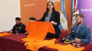 La secretaria de Asuntos Penales del Ministerio de Justicia y Seguridad de Santa Fe, Lucía Masneri, junto a funcionarios del Servicio Penitenciario, exhiben los uniformes naranja.