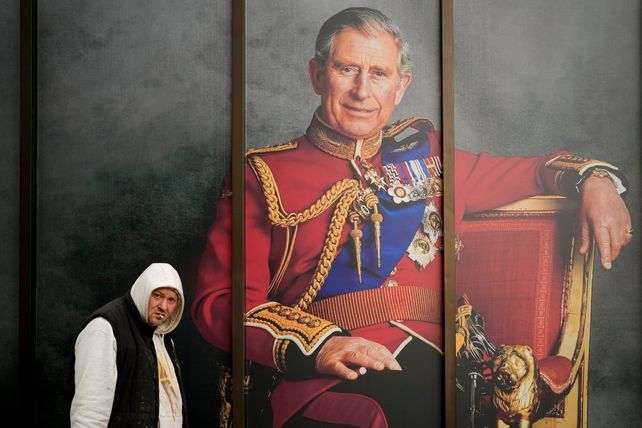 Un hombre camina frente a un retrato de Carlos III en la vía pública del centro de Londres.