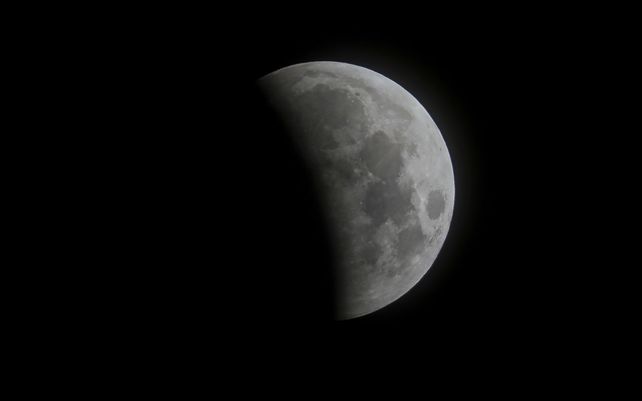 El progreso del eclipse lunar se ve detrás de las nubes sobre la playa de Santa Mónica en California. El primer eclipse lunar total en más de dos años coincide con una superluna de un gran espectáculo cósmico.