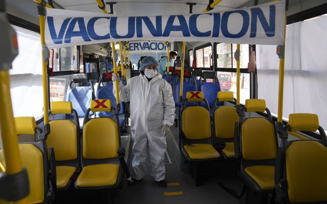 Un trabajador sanitario arriba de un bus utilizado para la vacunación en El Alto.
