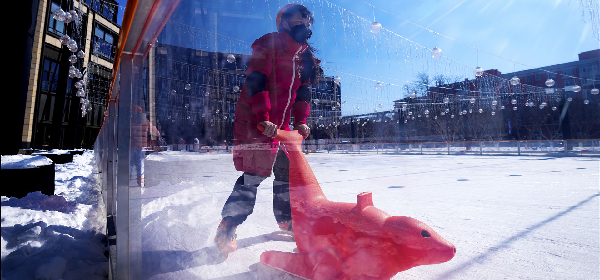 Una niña juega a patinar sobre hielo durante las vacaciones escolares frente a un centro comercial en Beijing, el lunes 14 de febrero de 2022.