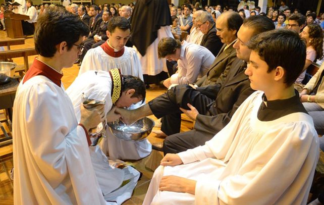 En la mira. El sacerdote Urrutigoity besa los pies de los fieles durante la liturgia.