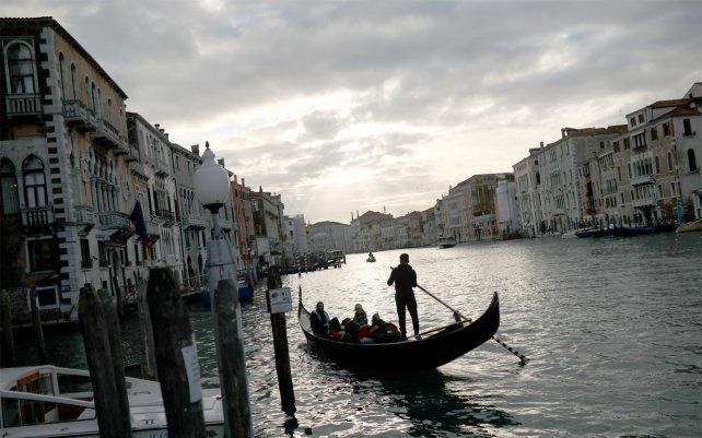 Gondoleros llevan a los turistas a lo largo del Gran Canal. Los países del G-7 dicen que están listos para tomar medidas para amortiguar los impactos económicos del nuevo brote de coronavirus.