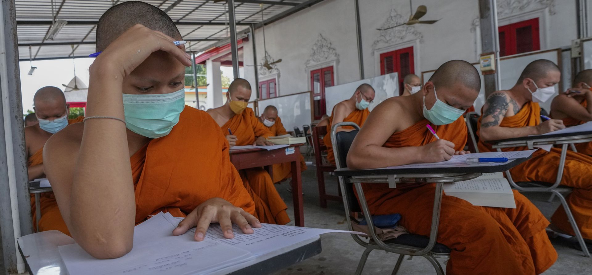 Monjes budistas toman una prueba del idioma pali litúrgico en Wat Molilokayaram en Bangkok, Tailandia, el jueves 20 de enero de 2022.