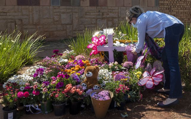 Christine Wright deja flores fuera del complejo donde vivía la familia Dickason antes de su emigración a Nueva Zelanda, en Pretoria, Sudáfrica, el jueves 23 de septiembre de 2021. Tres niñas que fueron asesinadas la semana pasada en un crimen que conmocionó a Nueva Zelanda.