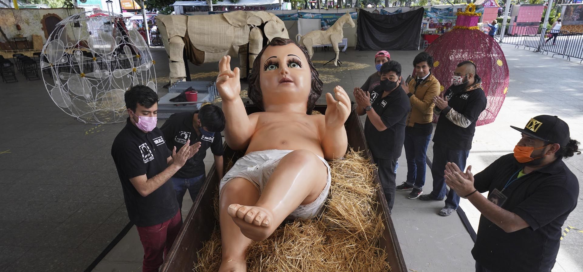 La familia Gómez Resendiz aplaude después de colocar una estatua gigante del Niño Jesús durante los preparativos para las celebraciones navideñas en una plaza en el distrito Iztapalapa de la Ciudad de México. Foto: AP