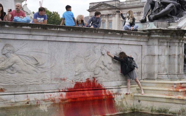 Manifestantes del grupo activista climática Extinction Rebellion embadurnan de pintura roja el Monumento a la Reina Victoria fuera de las puertas del Palacio de Buckingham en protesta contra la caza de animales, en Londres.