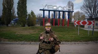 Una joven soldado ucraniana posa ante el cartel de ingreso a Jersón (en cirílico). La ciudad sufrió casi 9 meses de ocupación rusa.&nbsp;