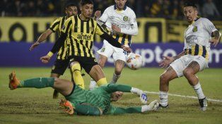 Damián Martínez intenta, pero no logra impactar la pelota ante el arquero de Peñarol.