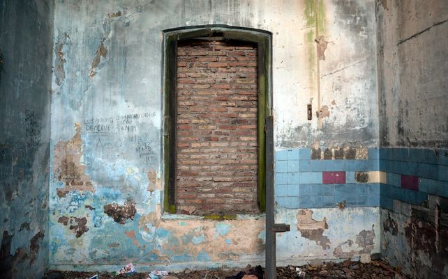 Una de las tantas ventanas tapiadas y unos pocos azulejos de colores en un rinc&oacute;n.