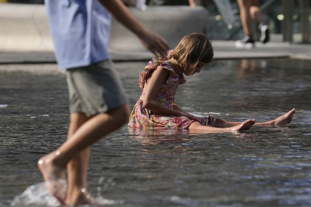 Una niña juega en una fuente pública en Milán.