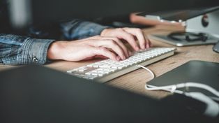 Person typing on a keyboard, representing the use of proposal software to create effective sales proposals.