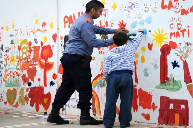 Agentes de la Policía Comunitaria junto a chicos y vecinos realizando el mural.