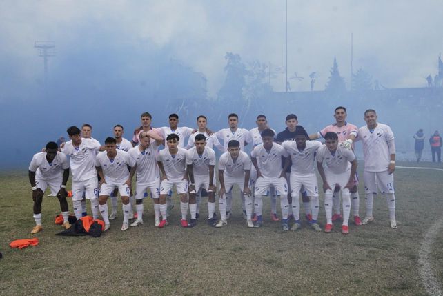 Tremenda postal de titulares y suplentes de Argentino, con la tribuna y el humo de las bengalas detrás.