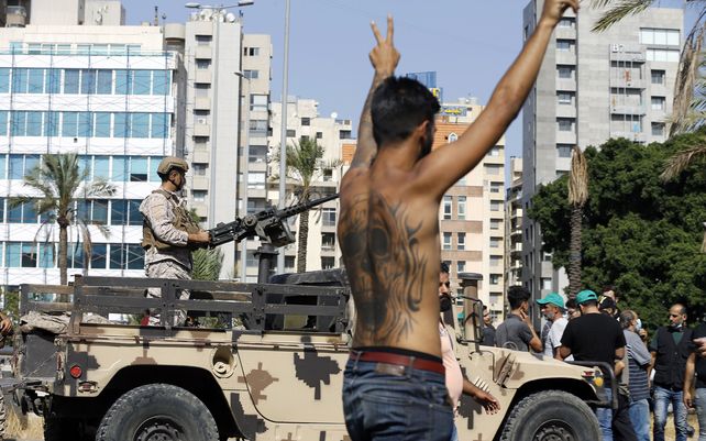 Un soldado del ejército se para en un vehículo mientras un partidario del Hezbollah chiíta muestra el signo de la victoria durante los enfrentamientos armados que estallaron durante una protesta en el suburbio de Dahiyeh