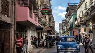 Colorida postal de las que muestra cotidianamente el centro de La Habana, con el avance de un auto antiguo.