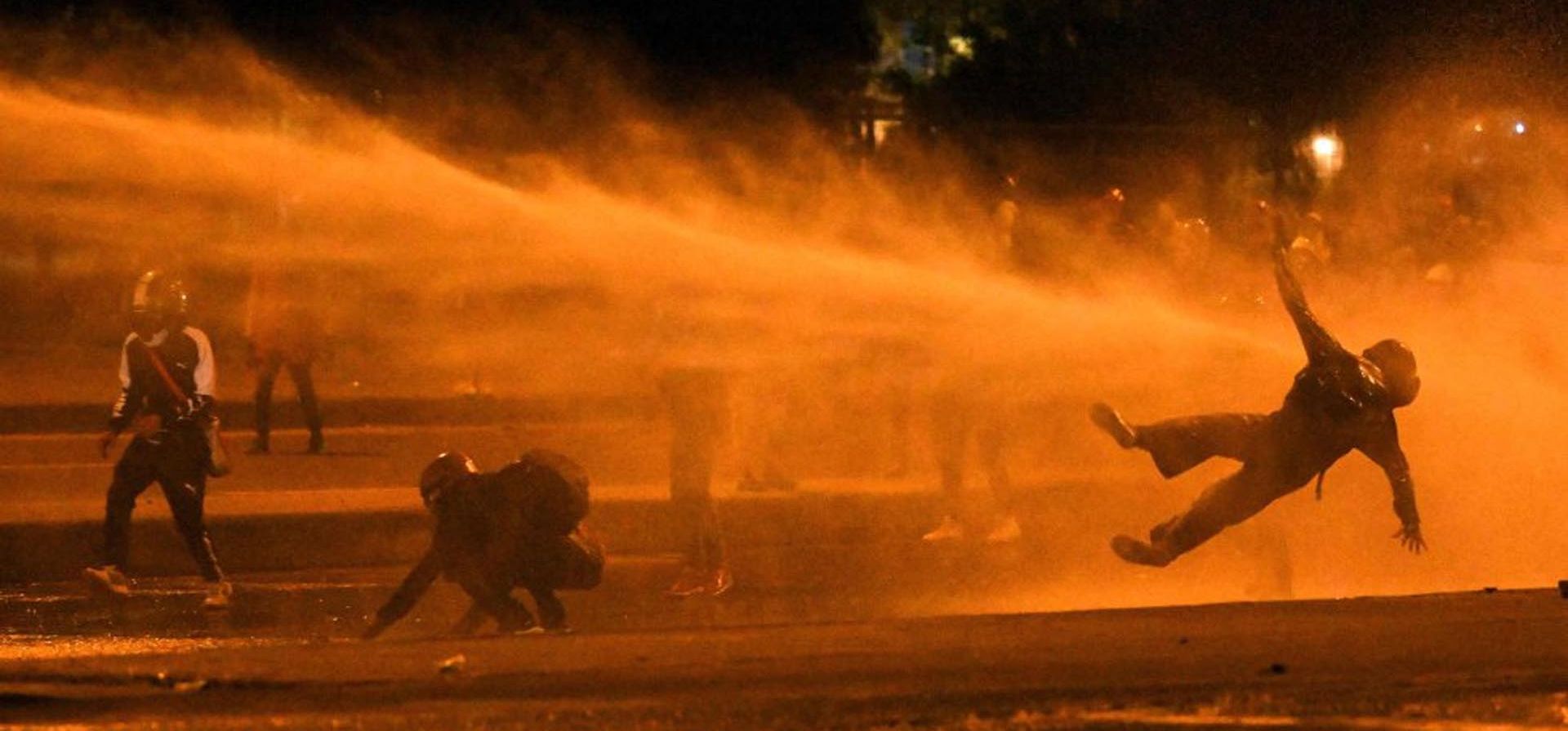 Un manifestante cae al ser alcanzado por un cañón de agua durante los enfrentamientos con la policía antidisturbios en medio de las continuas protestas contra el Gobierno del presidente colombiano Iván Duque en Bogotá el 12 de junio de 2021. Decenas de personas han muerto en las protestas que estallaron en todo el país el 28 de abril. Foto: AFP