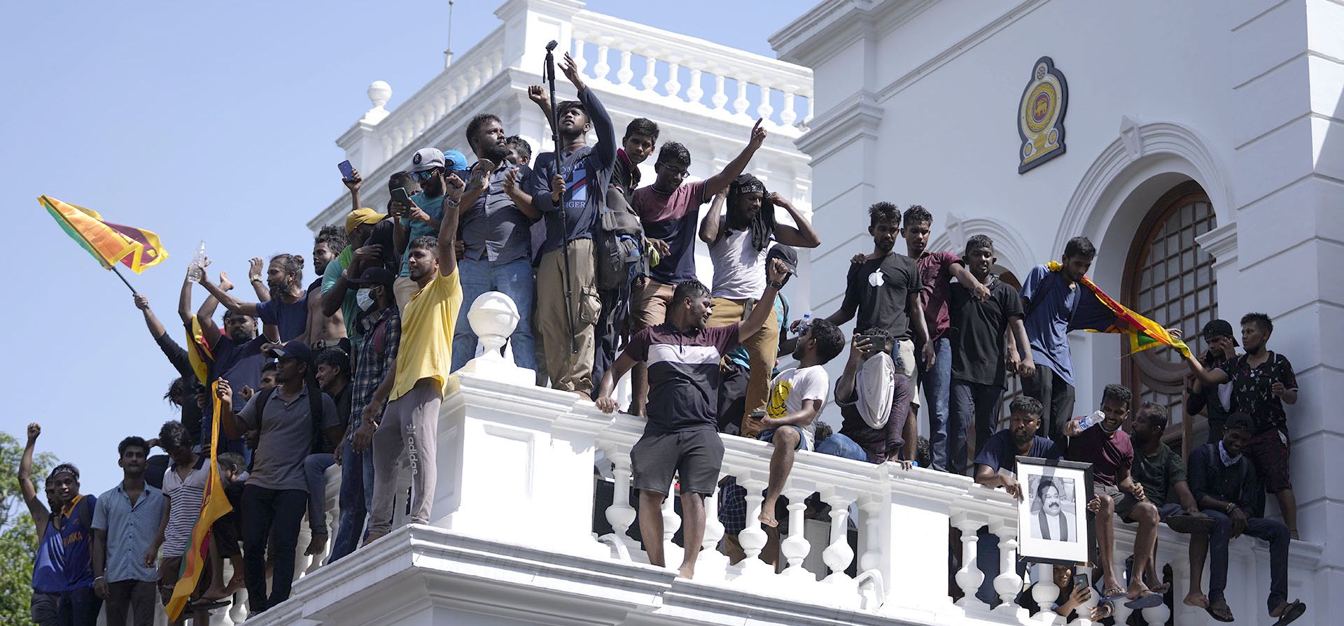 Manifestantes con banderas nacionales, después de irrumpir en la oficina del primer ministro Ranil Wickremesinghe, exigiendo su renuncia después de que el presidente Gotabaya Rajapaksa huyó del país en medio de la crisis económica en Colombo, Sri Lanka, el miércoles 13 de julio de 2022.