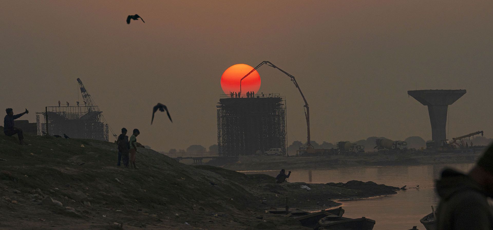 Obreros trabajan en un sitio de construcción a orillas del río Ganges mientras se pone el sol en Prayagraj, India, el jueves 22 de diciembre de 2022. (Foto AP/Rajesh Kumar Singh)