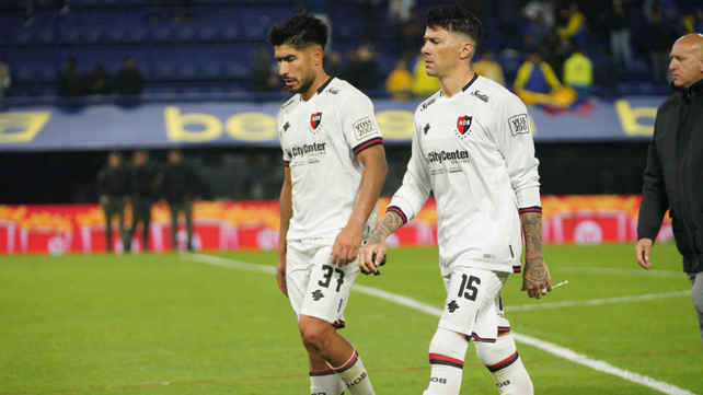 Luciano Lollo y Víctor Cuesta dejan el césped de la Bombonera, golpeados por la caída. 