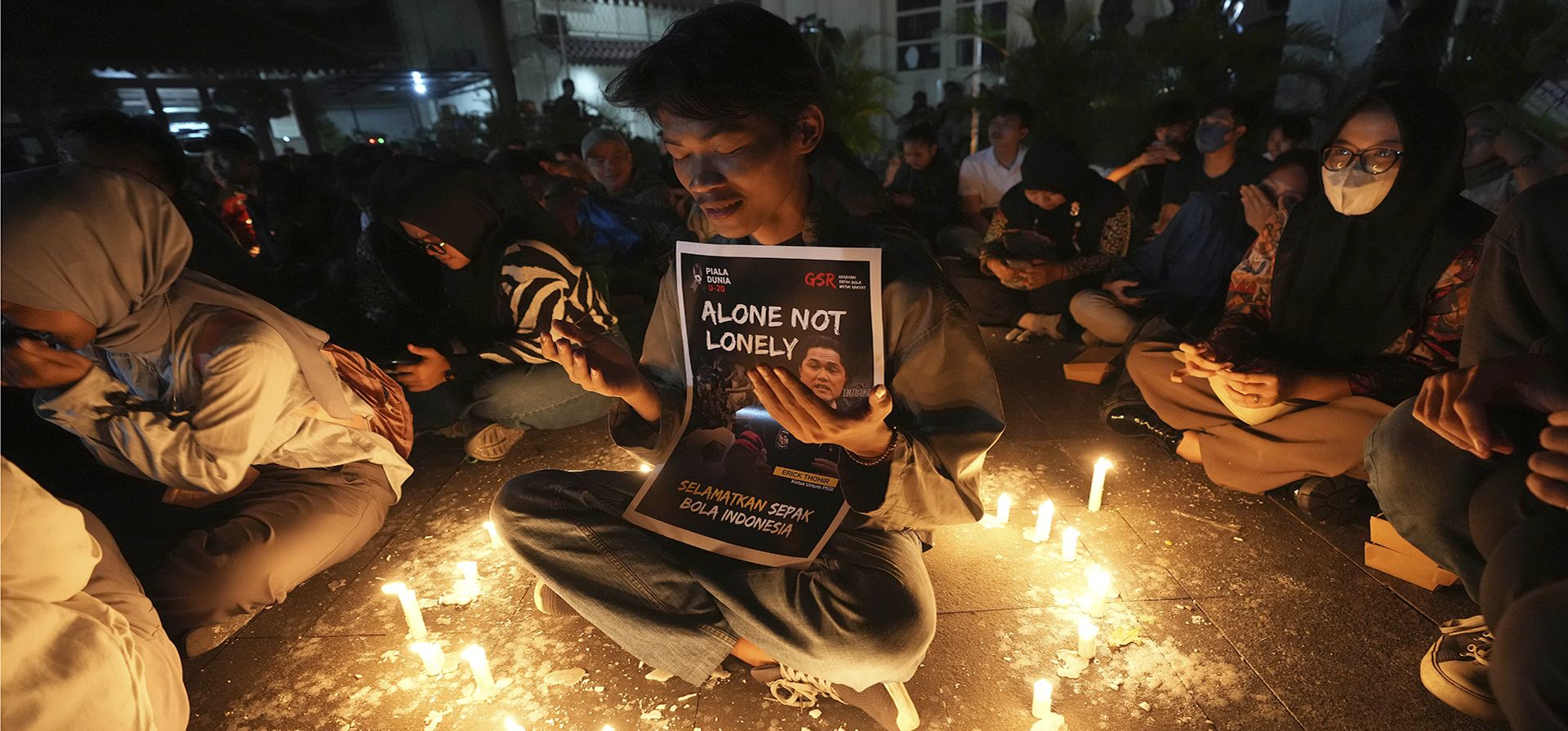 Aficionados al fútbol indonesios encienden una vela durante una manifestación expresando su decepción por la destitución del país como anfitrión de la Copa Mundial Sub-20 de la FIFA, en Yakarta, Indonesia, el martes 4 de abril de 2023. (Foto AP/Tatán Syuflana)